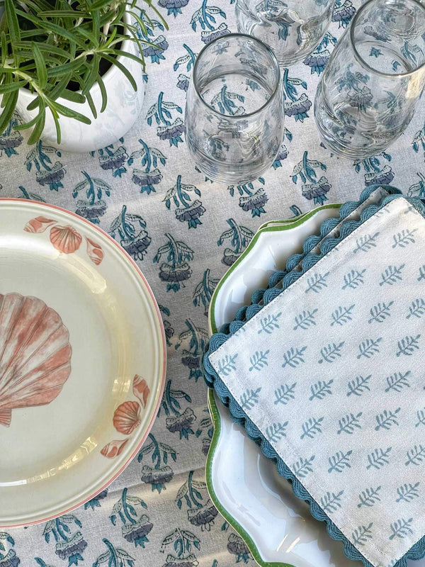 Blue and white block printed cocktail napkins on table beside plate