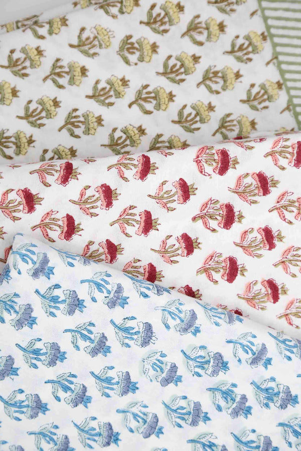 Three block print tablecloths stacked on each other in green, red, and blue
