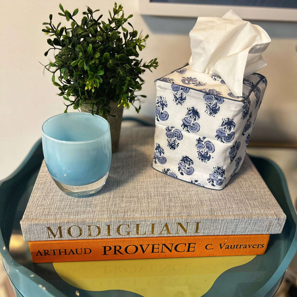 Blue and white block printed tissue box cover on table with books and candle