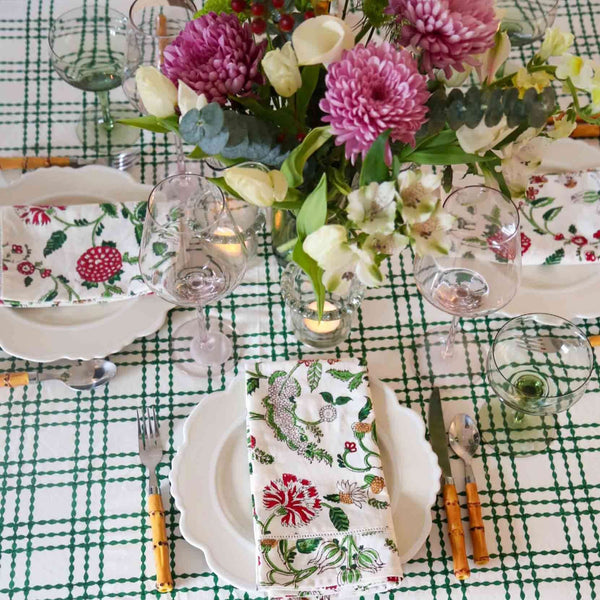 Table set with green and white block printed tablecloth, plates, and flowers