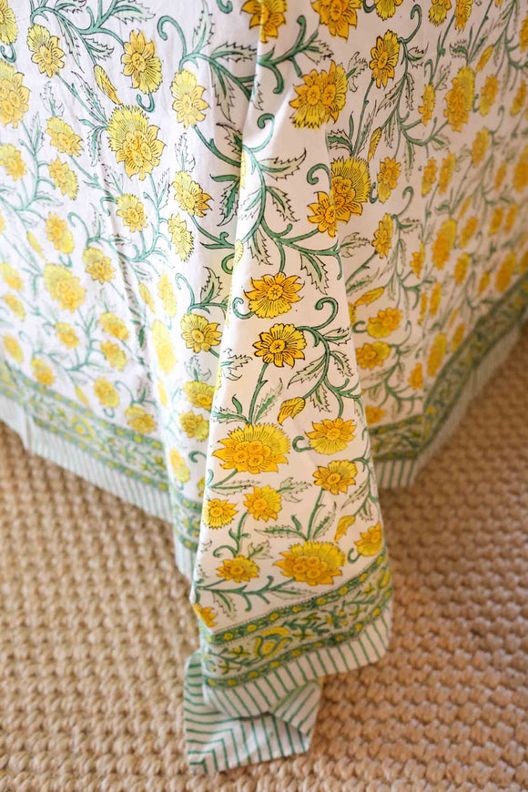 Corner of table with yellow and green block printed tablecloth