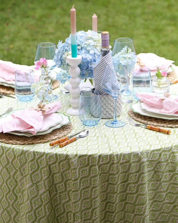 Table set with plates, blue wine glasses, and green round tablecloth
