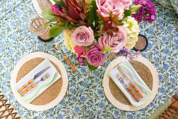 Table setting with flowers and placemats on a green block printed tablecloth