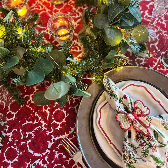 Red block printed tablecloth with plate, napkin and flowers