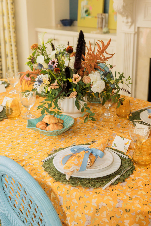 Inslee Marigold Linen Tablecloth set with floral centerpiece, plates, and glassware for an elegant dining experience.