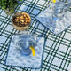 White block print cocktail napkins with martinis on green striped tablecloth