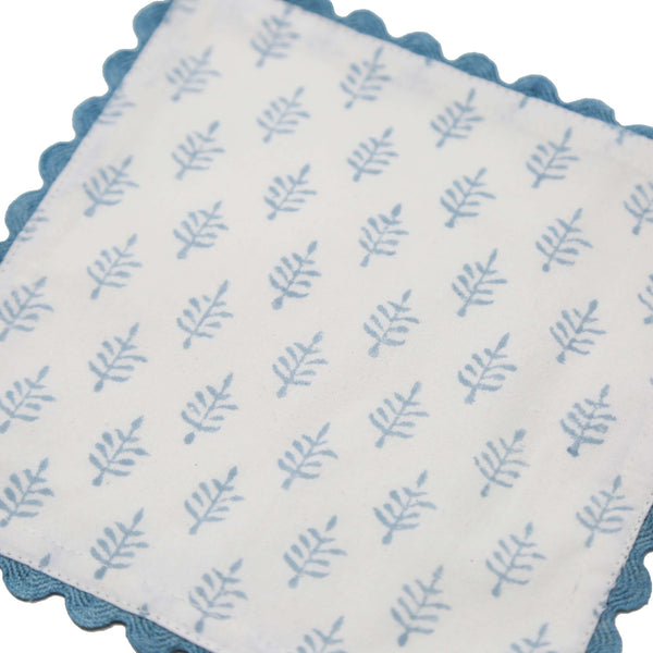 White block print cocktail napkin with small blue trees and blue border