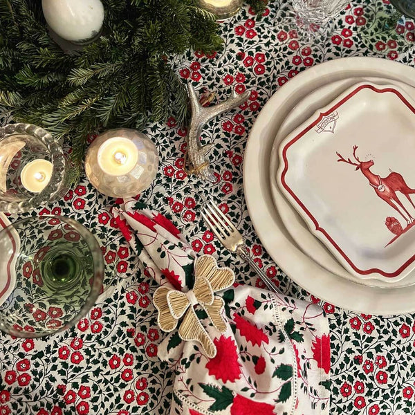 Red, green and white block printed napkin on table with candles and Christmas china