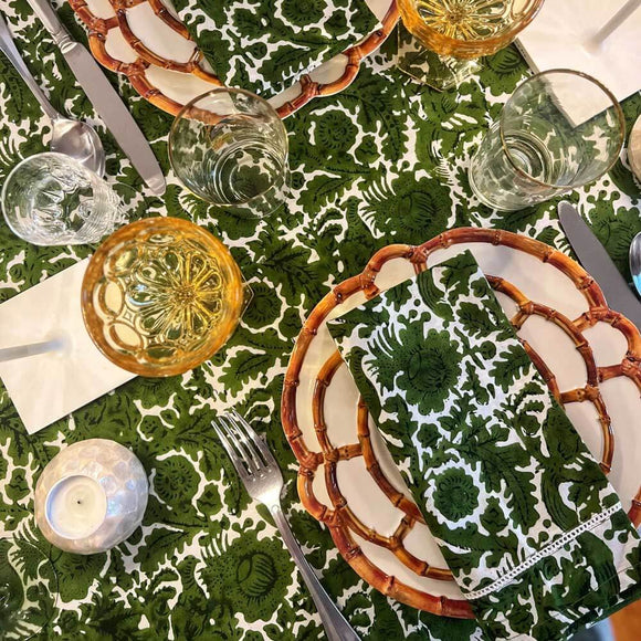 Table setting with green block print napkin on bamboo rimmed plates