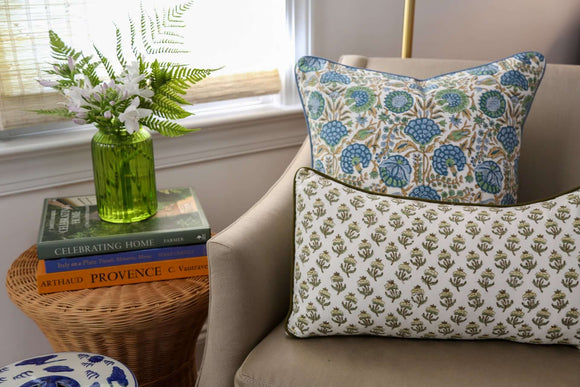 Two block printed pillows on living room chair beside green plant