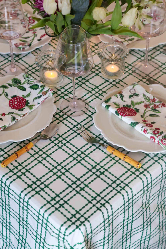 Table set with green and white block printed rectangle tablecloth, plates, and flowers