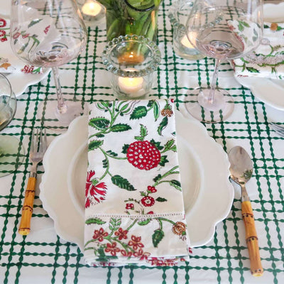 Table setting on green and white block printed tablecloth with plate, napkin, and bamboo silverware