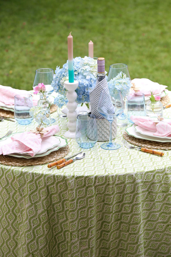 Table set with plates, blue wine glasses, and green round tablecloth