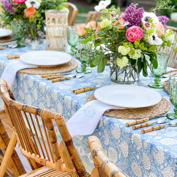 Long banquet table set with blue block printed tablecloth and flower centerpieces