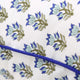Close up of blue and green floral pillow cover with blue pipping