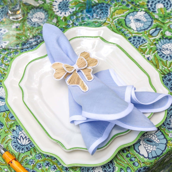 Table setting with plates, napkin and napkin ring on a green tablecloth
