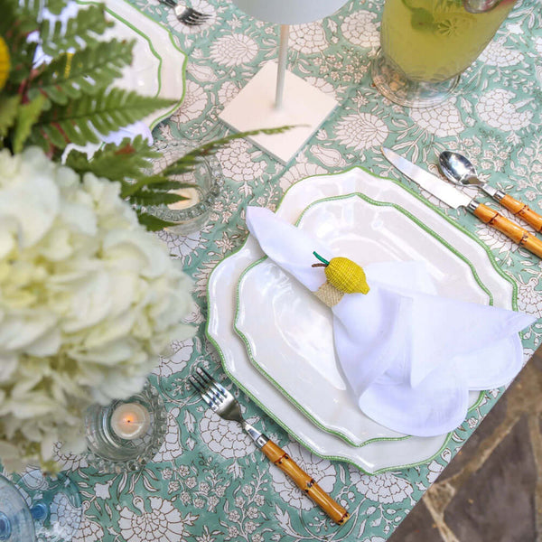 Green block printed tablecloth with flower centerpiece and white napkins